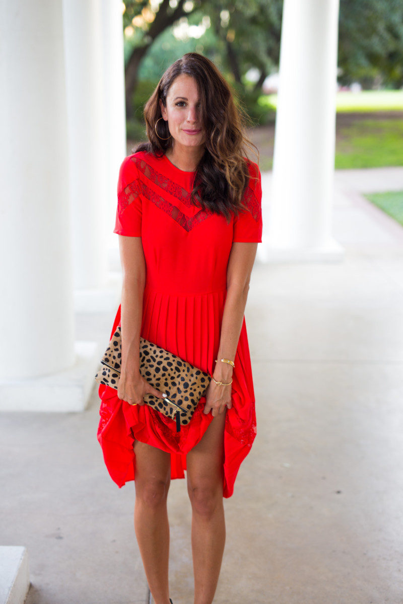 The Miller Affect wearing a red lace dress and holding a leopard clutch
