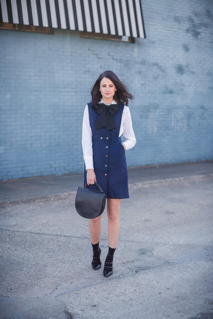 Amanda Miller wearing a navy pinafore dress with a black bow tie