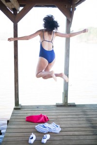 Amanda Miller jumping in a navy Heat Smart One-Piece Swimsuit