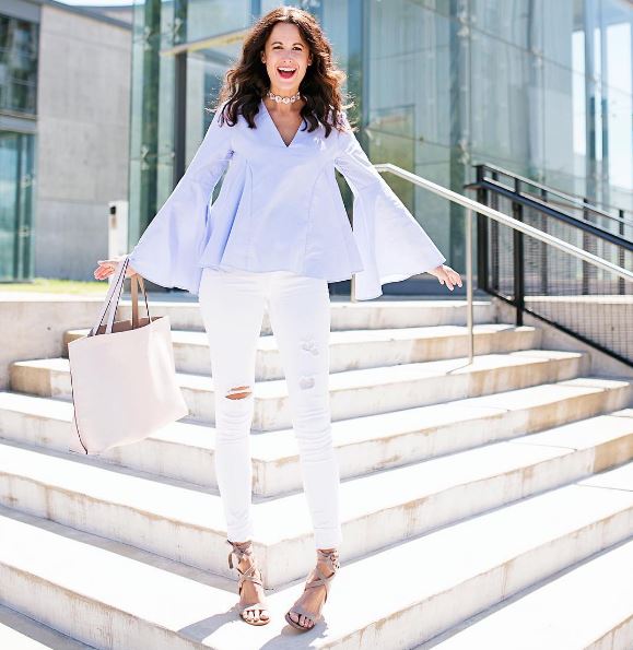 blue bell sleeved blouse with white distressed skinny jeans and a pink tote