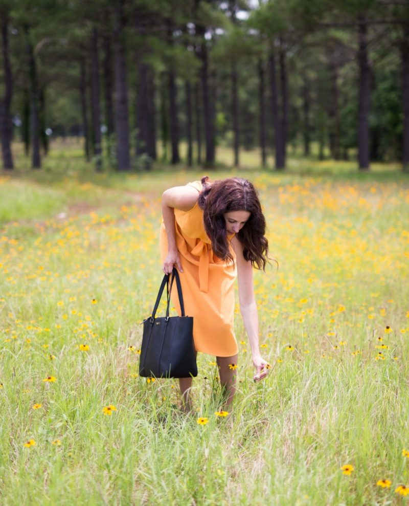 Amanda Miller picking wildflowers in a yellow Ann Taylor dress