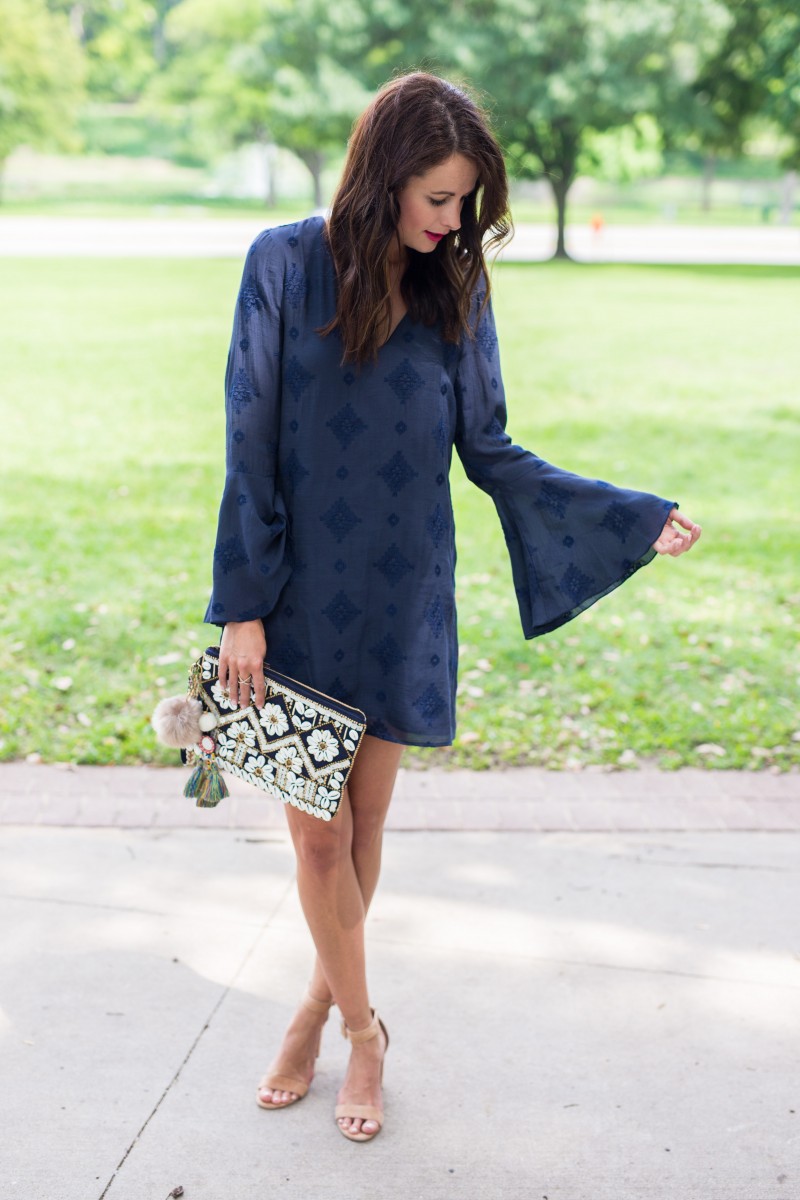 Amanda Miller wearing a navy blue WAYF bell Sleeved embroidered dress