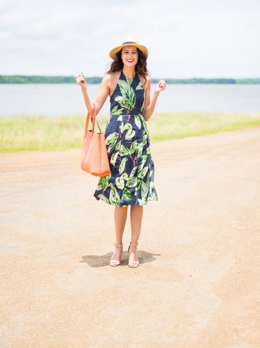 The Miller Affect twirling in a palm print dress while holding a reversible tote