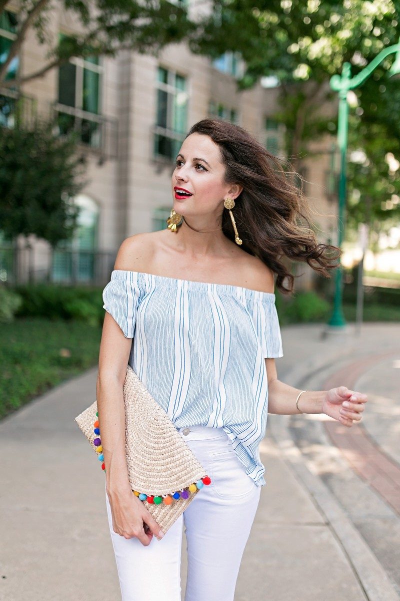 The Miller Affect wearing gold tassel earrings and a blue and white striped off the shoulder top