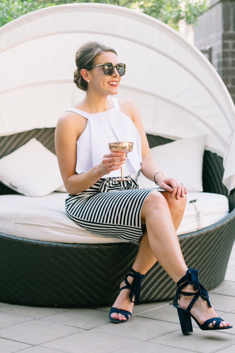 Fashion and Frills wearing a white crop top and a striped tie skirt