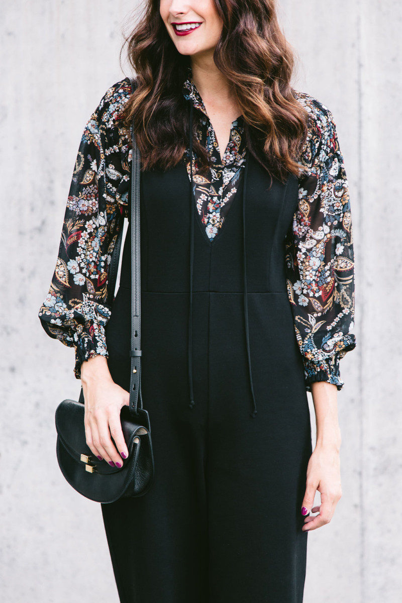 The Miller Affect wearing a black Leith jumpsuit from Nordstrom and a floral top from WAYF