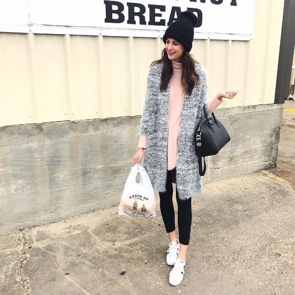 The Miller Affect wearing a super fuzzy grey cardigan, a black knit pom beanie, black leggings, and adidas neo sneakers