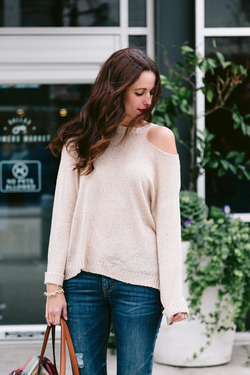 The Miller Affect wearing a bell sleeve sweater with a shoulder cut out