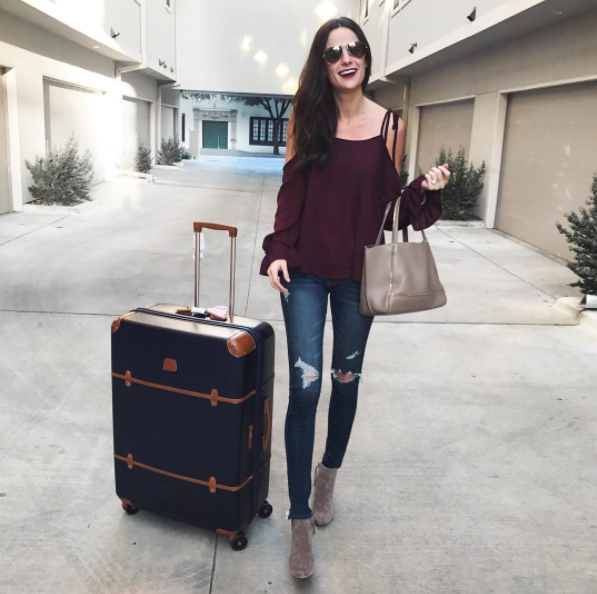 The Miller Affect in a burgundy silk cold shoulder top with Brics luggage