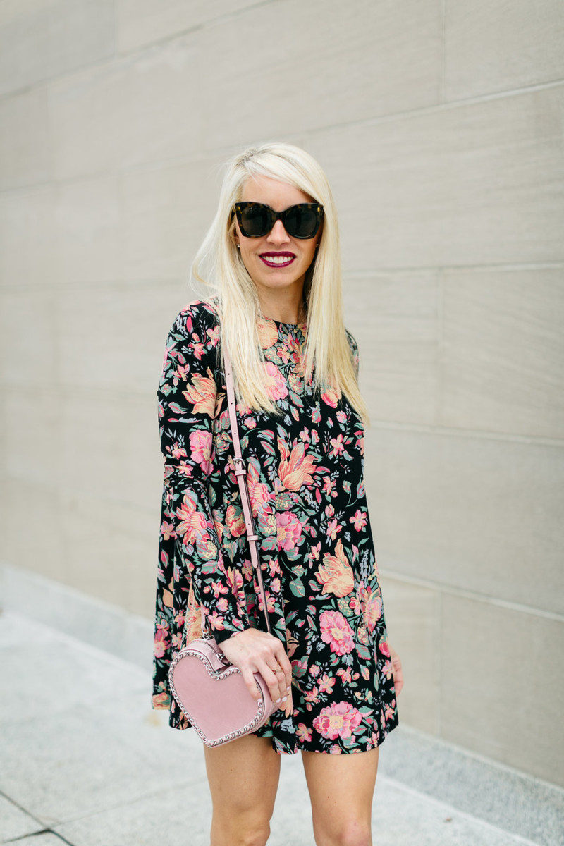 Jaime Shrayber wearing a black floral swing dress and a pink rebecca minkoff heart crossbody