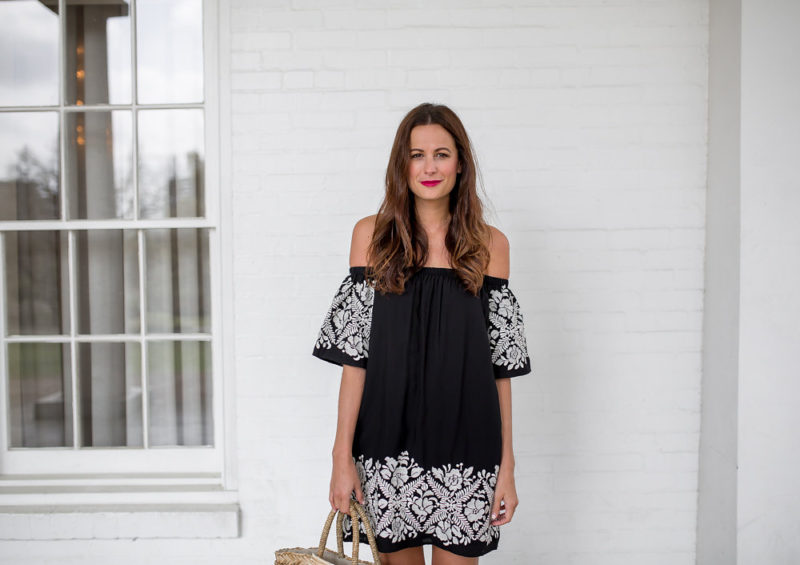 The Miller Affect wearing a black off the shoulder dress with white embroidered details