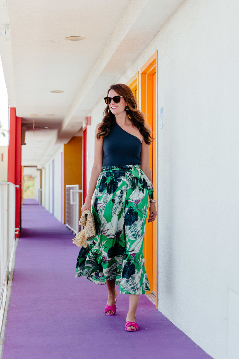 The Miller Affect wearing a navy one shoulder top with a tropical print maxi skirt