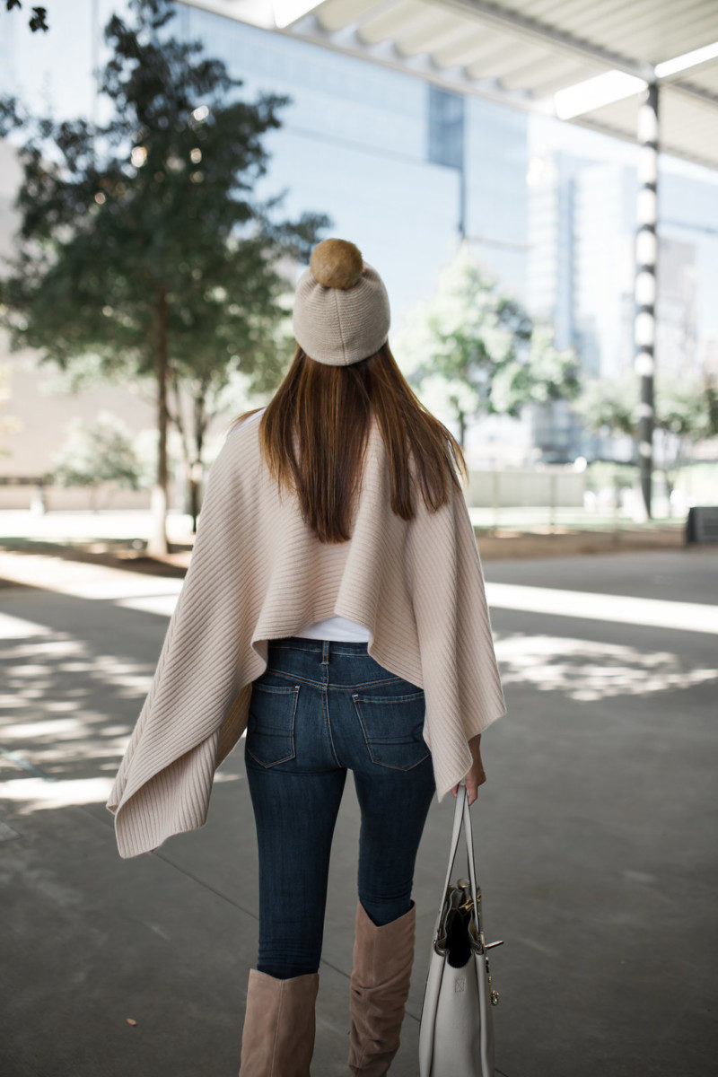 The Miller Affect wearing a fur pom beanie with a beige cashmere cape