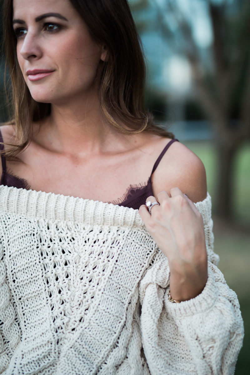 The Miller Affect wearing a beige cable knit sweater with a burgundy lace cami