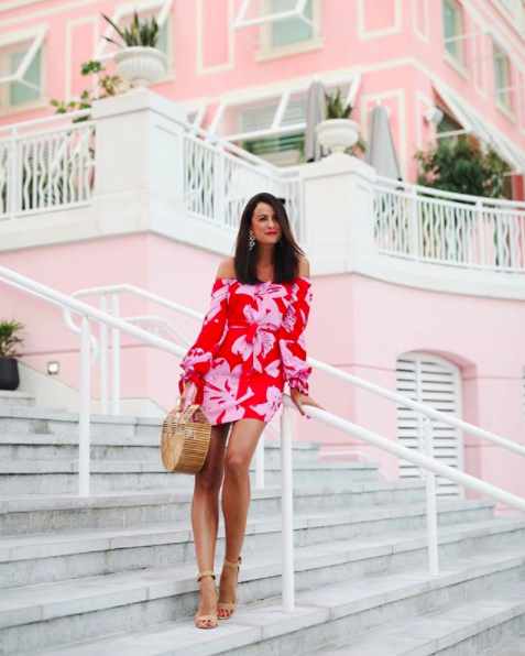 the miller affect wearing a pink and red off the shoulder tropical dress from Bardot
