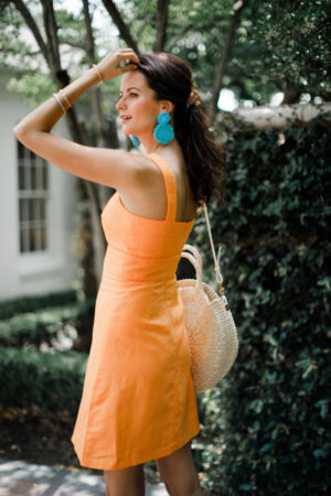 the miller affect wearing an orange linen dress to a summer wedding