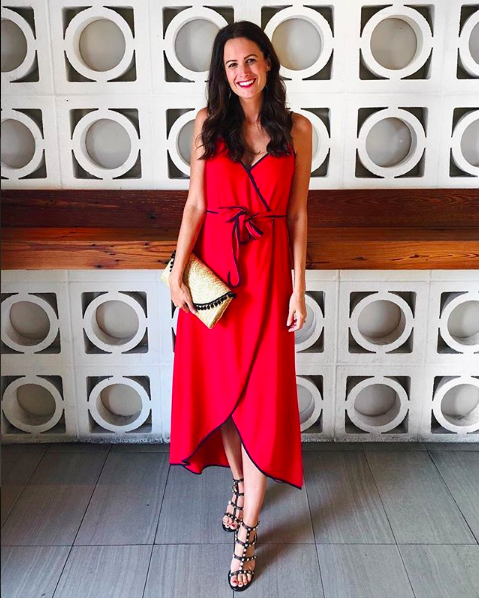 the miller affect wearing a red wrap dress with black trim
