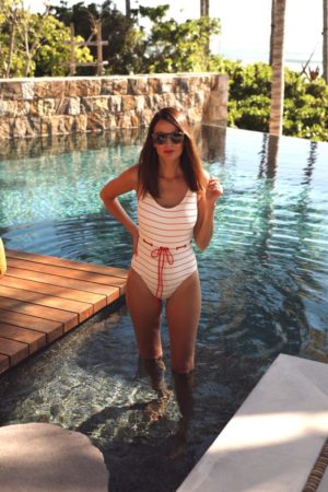 the miller affect wearing an orange striped one piece swimsuit