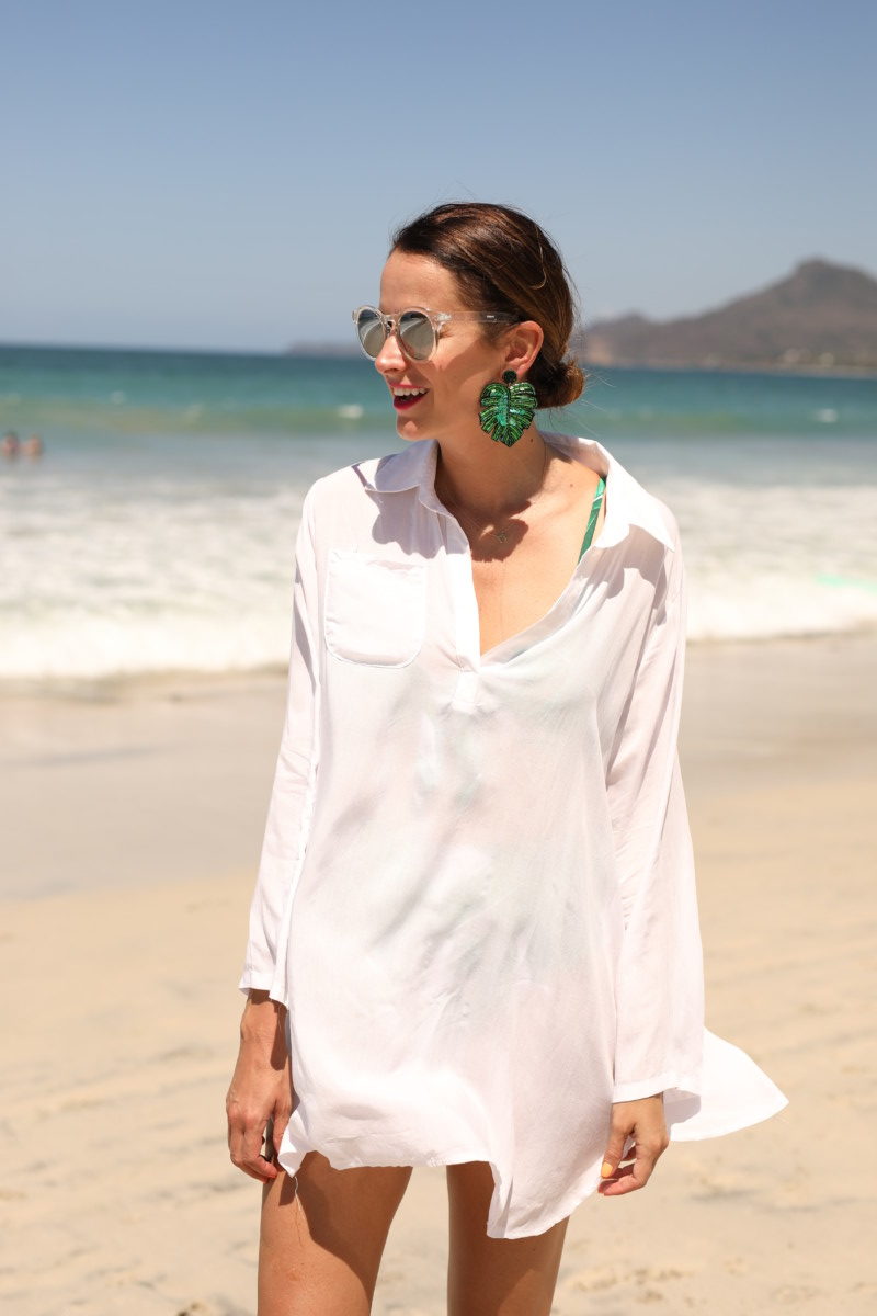 themilleraffect.com wearing a white shirt cover up and green palm earrings